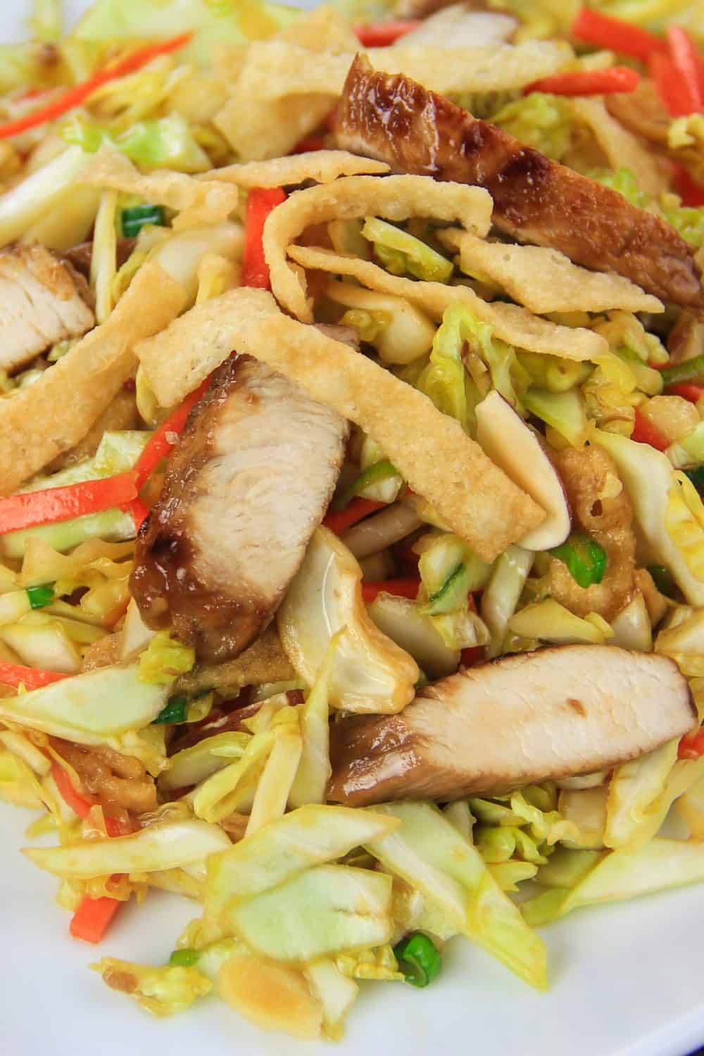 crunchy asian chicken salad recipe with simple ingredients that are so easy to throe together. #asianchickensalad #chinesechickensalad #asiansalad #sesamesalad #chickensalad close up image of an asian chicken salad with cooked chicken, shredded cabbage, carrot, cashews, and crispy wontons
