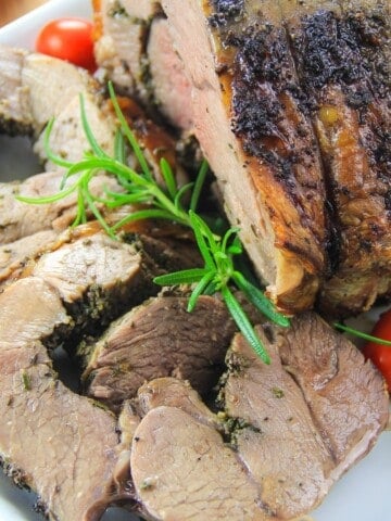 boneless roasted leg of lamb with rosemary and cherry tomato next to it