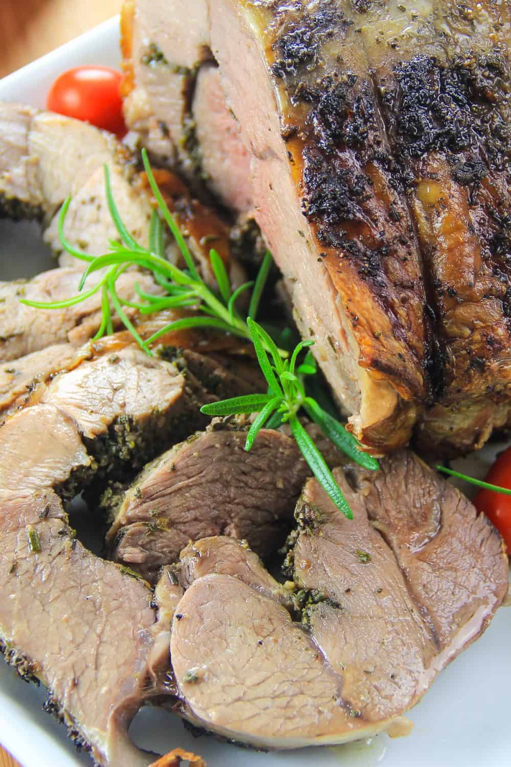 boneless roasted leg of lamb with rosemary and cherry tomato next to it