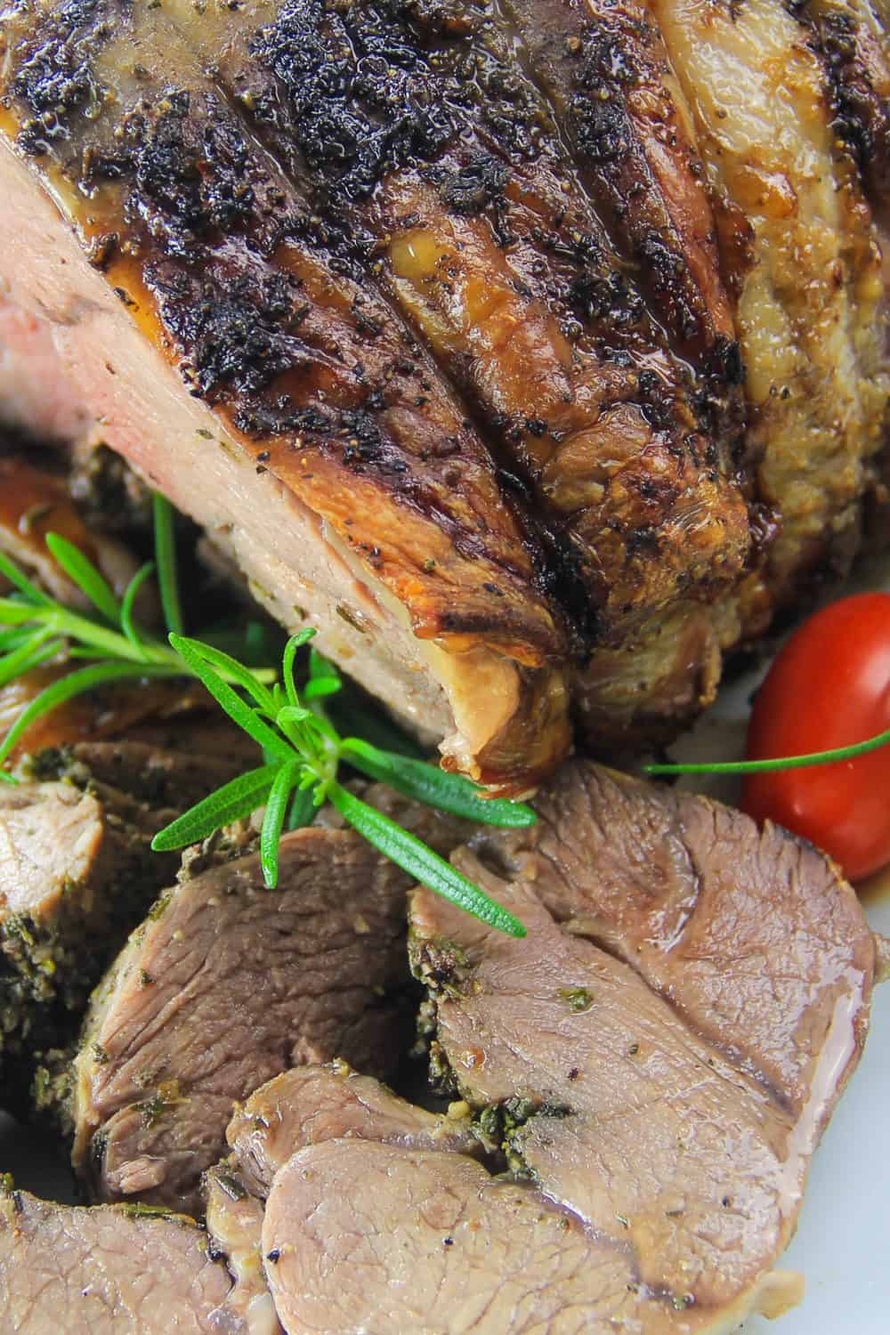 boneless roasted leg of lamb with rosemary and cherry tomato next to it