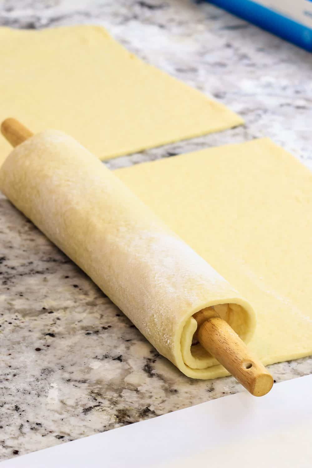 homemade Danish dough being rolled out with a rolling pin.