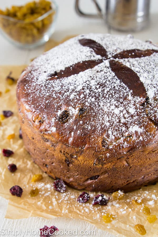 This buttery panettone bread recipe is loaded with fragrant citrus zest, dried cranberries, and golden raisins. The warm fluffy texture will blow your mind! #panettone #christmasbread #italianbread #italianchristmas panettone bread on brown parchment paper with powdered sugar on top