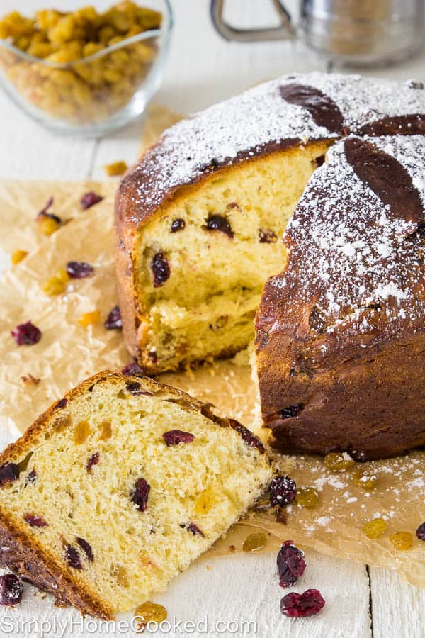 This buttery panettone bread recipe is loaded with fragrant citrus zest, dried cranberries, and golden raisins. The warm fluffy texture will blow your mind! #panettone #christmasbread #italianbread #italianchristmas sliced panettone bread on brown parchment paper