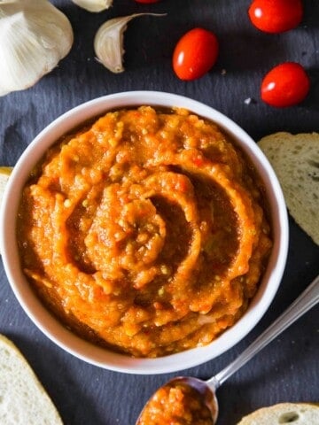 eggplant spread ikra, in a white bowl with tomatoes and bread around