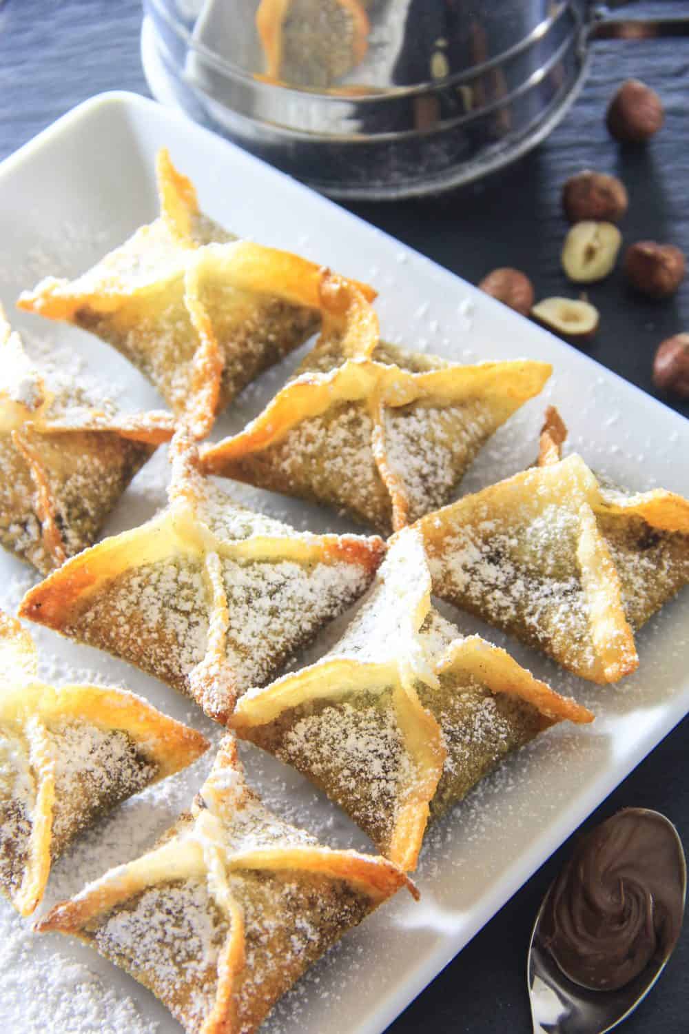 Nutella Wonton Recipe displayed on white platter with sprinkle of powdered sugar on top