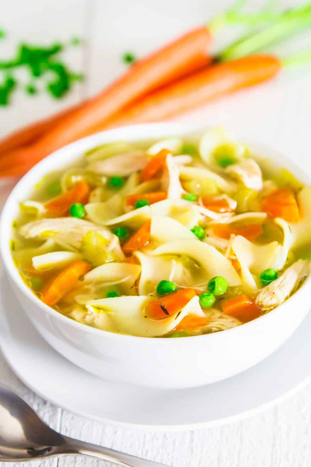Everyone needs a Chicken Noodle Soup from Scratch in their recipe book and this one loaded with carrots, celery and the extra snap of peas is going to become a family favorite. #chickennoodlesoup #noodlesoup #chickensoup #healthysoup #clearsoup #lowcaloriesoup