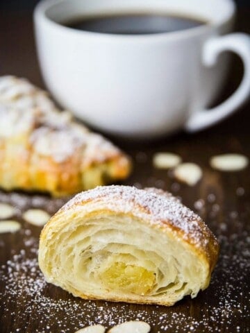 sliced almond croissant with a cup of coffee beside it