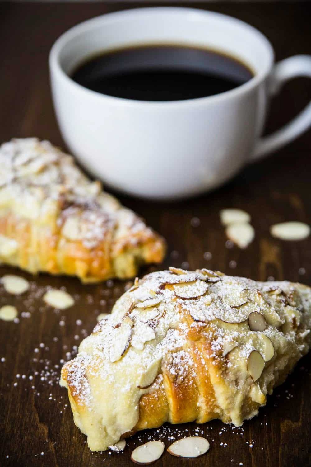 almond croissant with a cup of coffee beside it