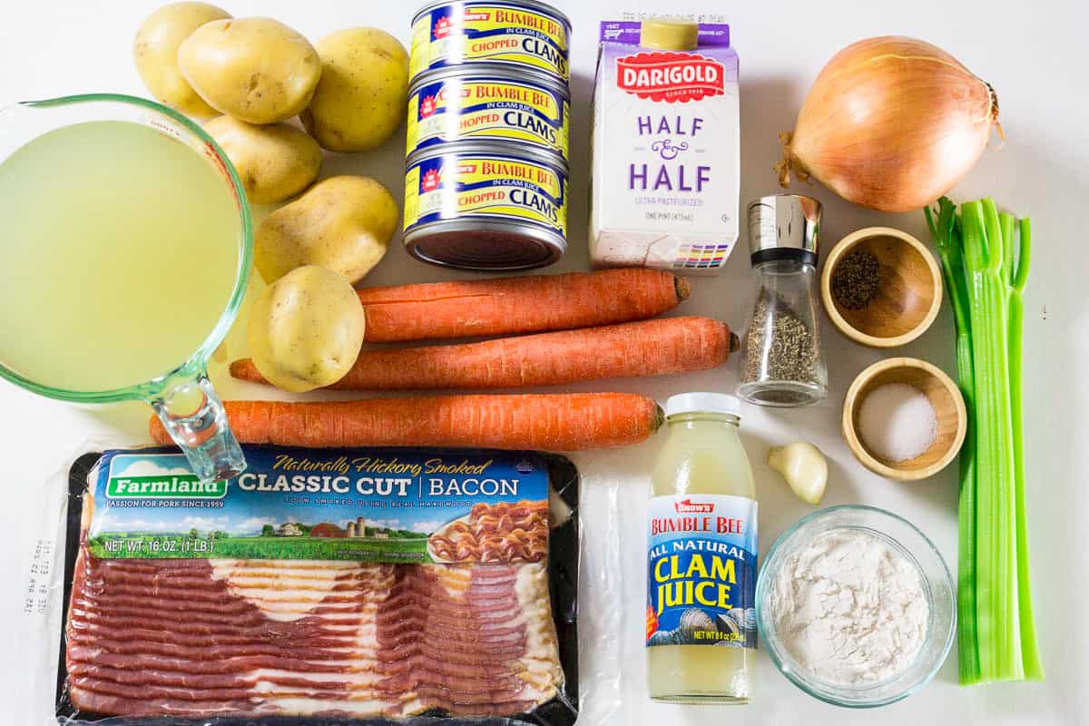 This Clam Chowder Soup recipe is a perfect meal that brings together a potato and cream base and the saltiness of clams with a light smoky bacon flavor. #clamchowder #chowder #seafoodchowder #clamsoup #seafoodsoup #creamysoup Ingredients for clam chowder soup laying on a flat white surface and photographed from above