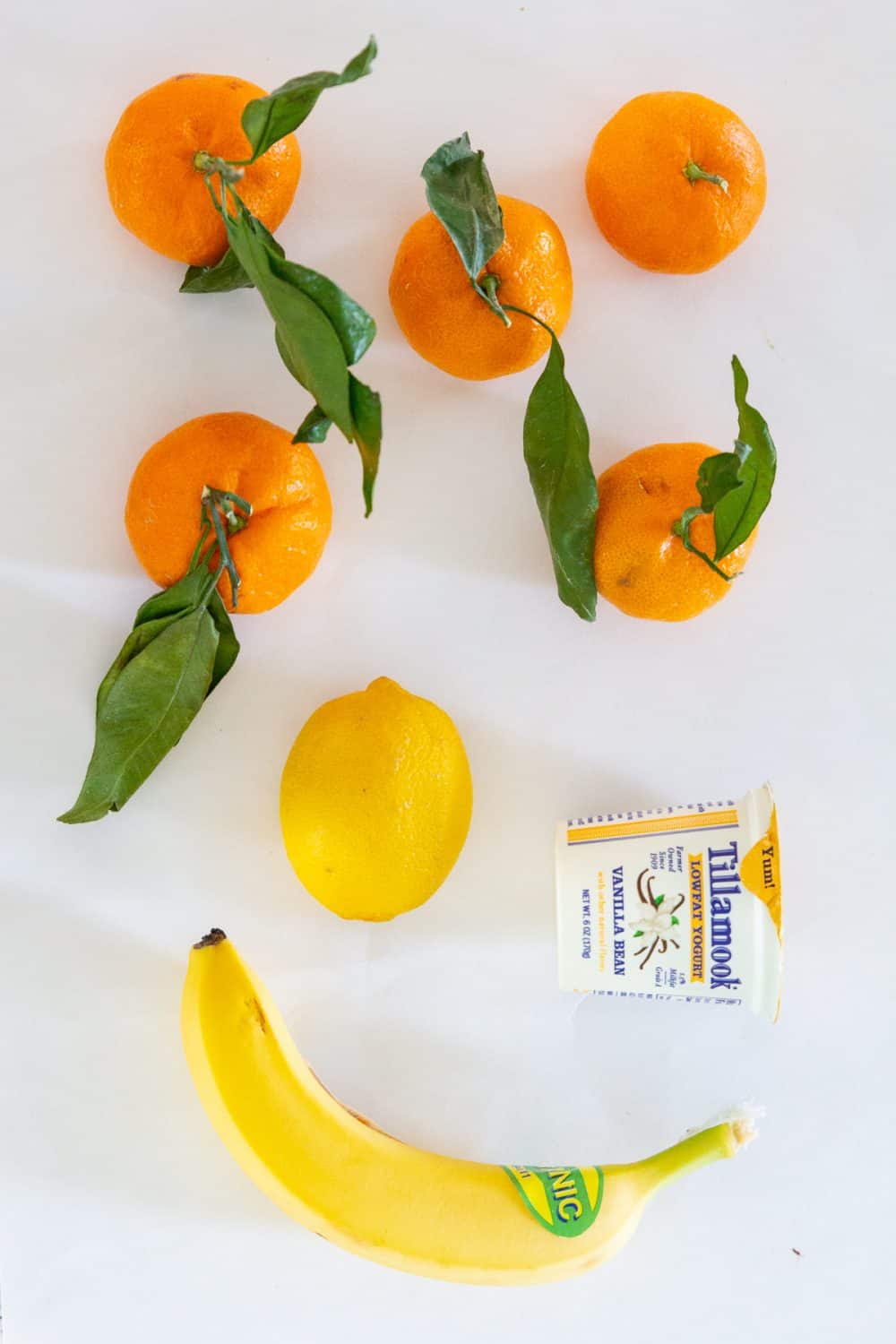 Ingredients needed for mandarin banana smoothie laying on a flat white surface