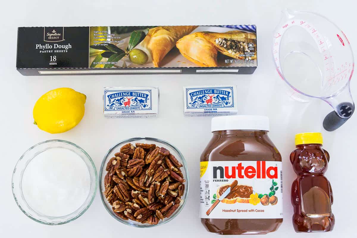Ingredients for baklava recipe with nutella laying on a flat white surface and photographed from overhead