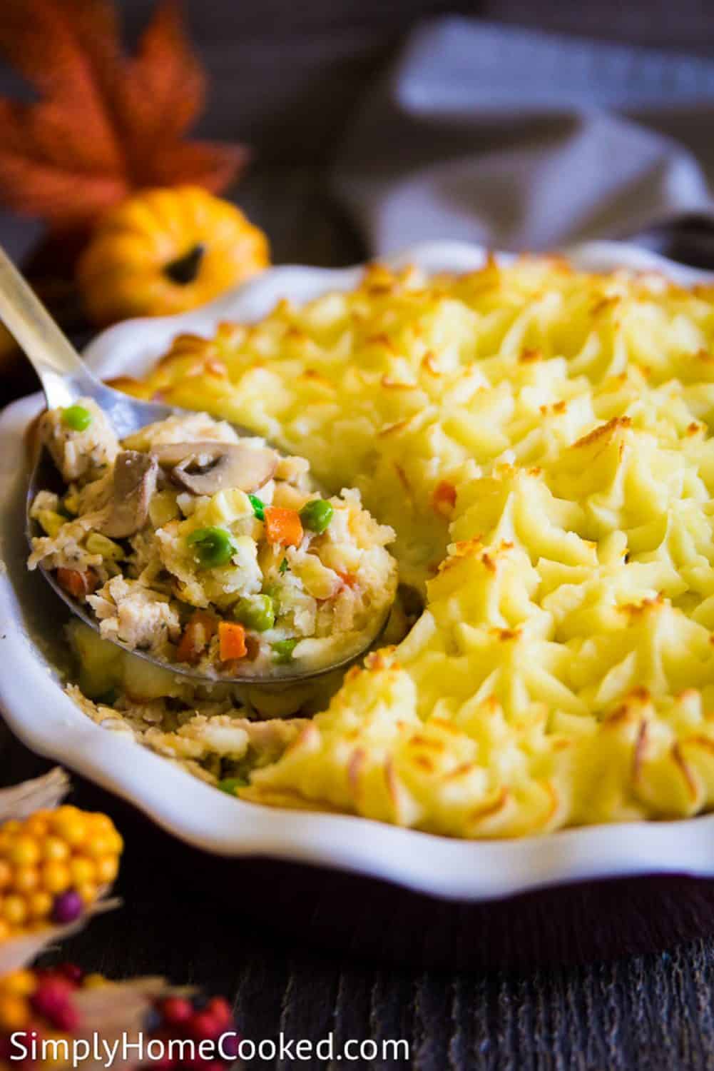 Easy and delicious thanksgiving turkey leftovers recipe! Make this tasty turkey shepherds pie! It's quick, simple, and so yummy. #turkeyleftovers #leftoverturkeyrecipe #shepherdspie #Turkeypie #savorypie a close up image of a shepherds pie with a filling made out of thanksgiving leftovers including peas, carrots, and corn