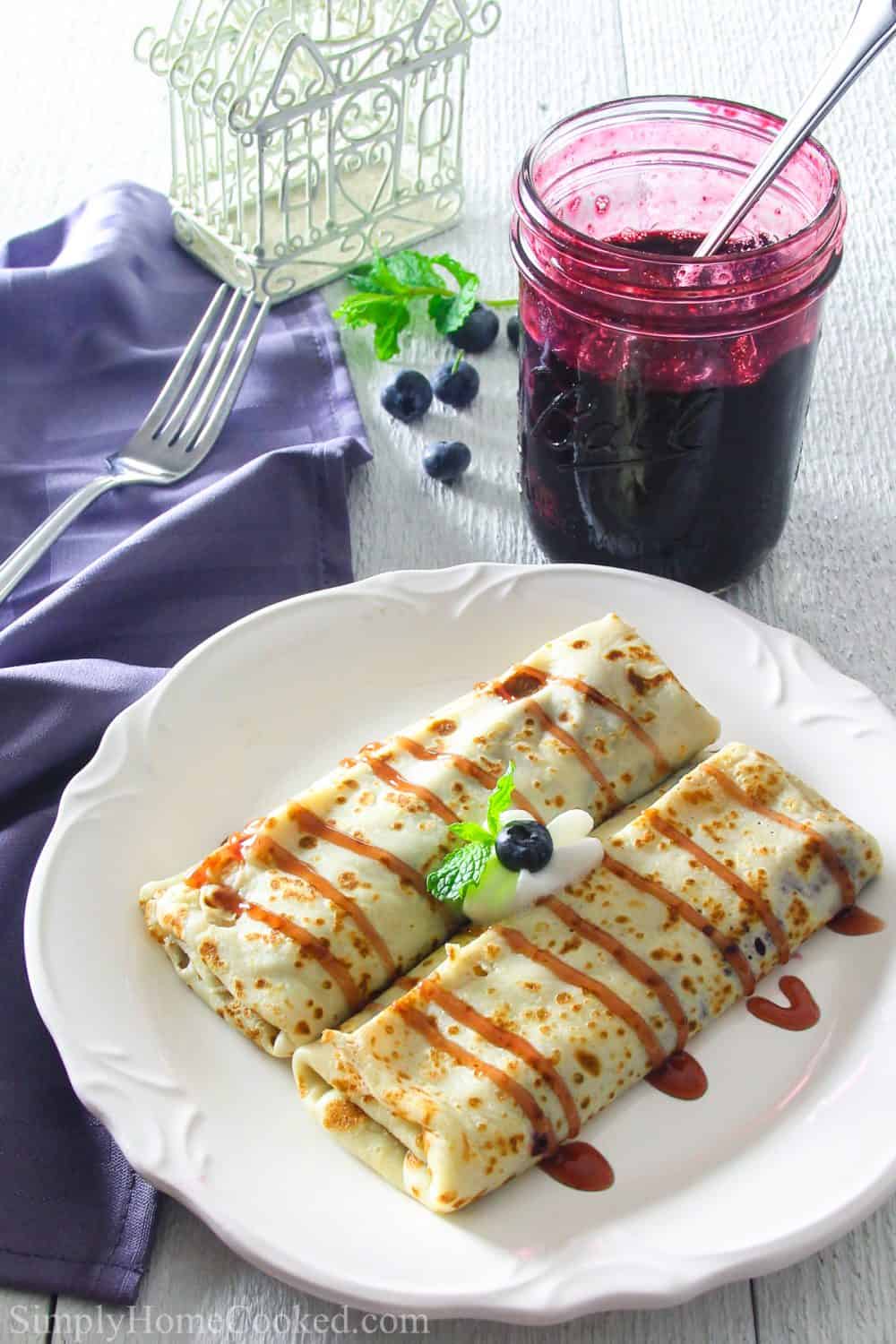Delicious crepes filled with homemade blueberry pie filling. This blueberry crepe recipe is an easy and quick dessert everyone will love. #crepes #creperecipe #easycrepes #blueberrycrepes Add a drizzle of blueberry syrup or your favorite real maple syrup to the top of this beautifully cooked blueberry breakfast crepe recipe for a delicious breakfast treat.