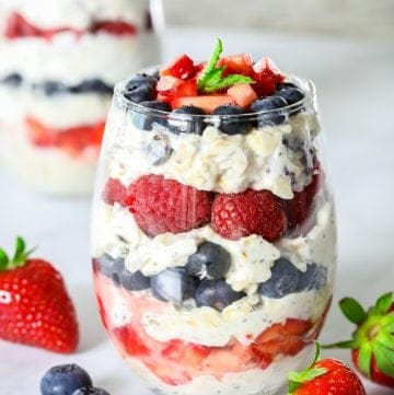 greek yogurt and berry parfait in a wine glass with mint leaves on top as garnish