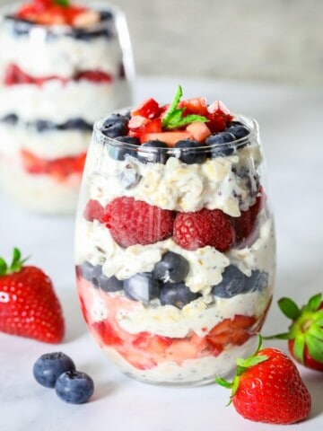 greek yogurt and berry parfait in a wine glass with mint leaves on top as garnish