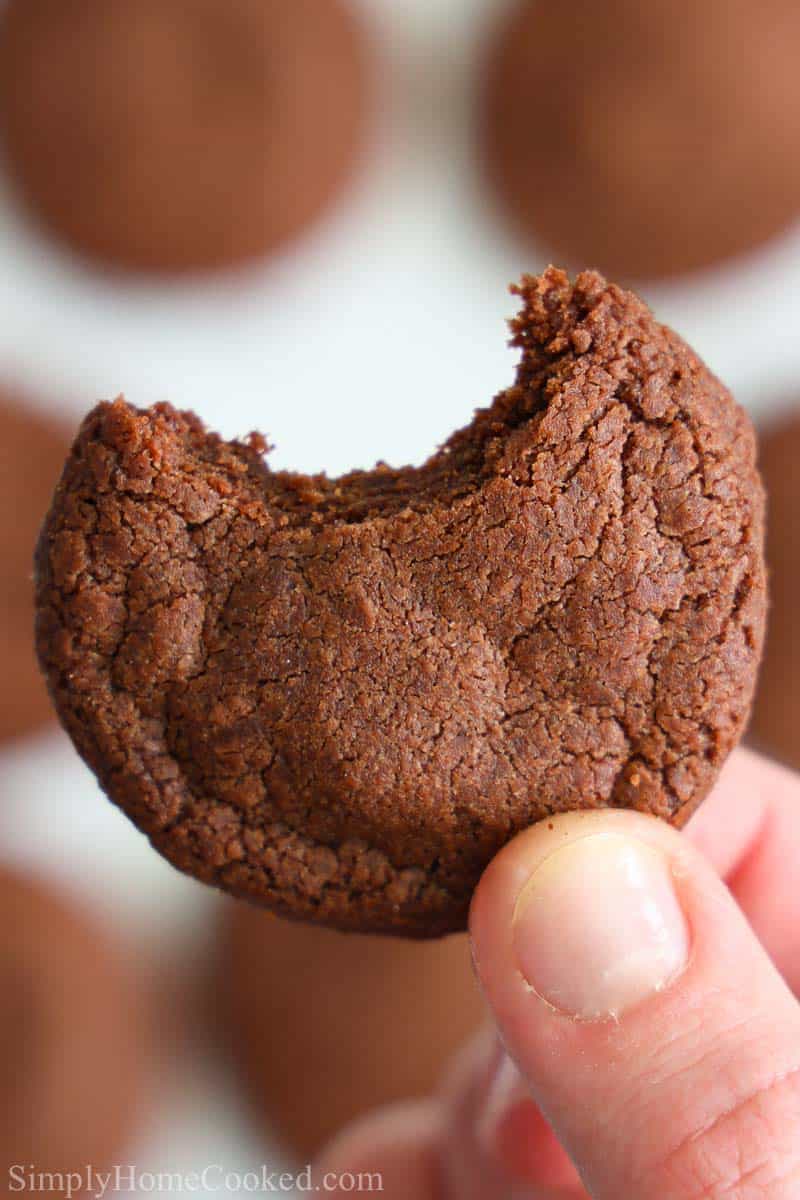 Soft and chewy Nutella cookies that are super easy to make and have an intense chocolate Nutella flavor. These are always a crowd pleaser. Which makes them great for parties! #nutella #nutellacookies #chocolatecookies #chewynutellacookies #easycookies Close up image of a hand holding a bitten Nutella cookie