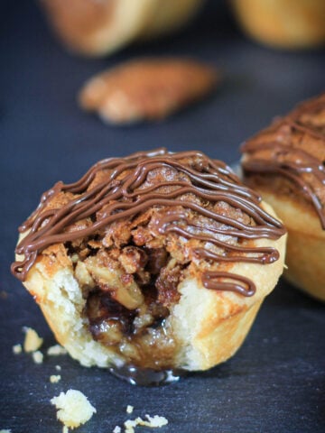 Vertical close up image of Pecan Tassies, one missing a bite.
