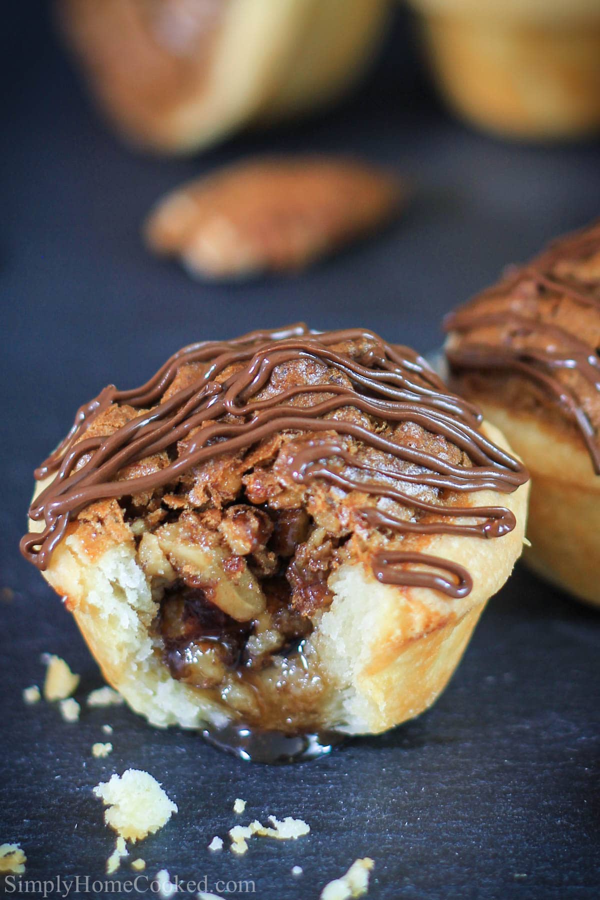 These mini pecan tassies are made of a buttery pie crust and filled with brown sugar and pecan filling. They're the perfect bite-sized treat! #minipecanpie #pecanpie #pecantassies #thanksgivingfood #thanksgivingdessert close up image of Pecan Tassies, one missing a bite.