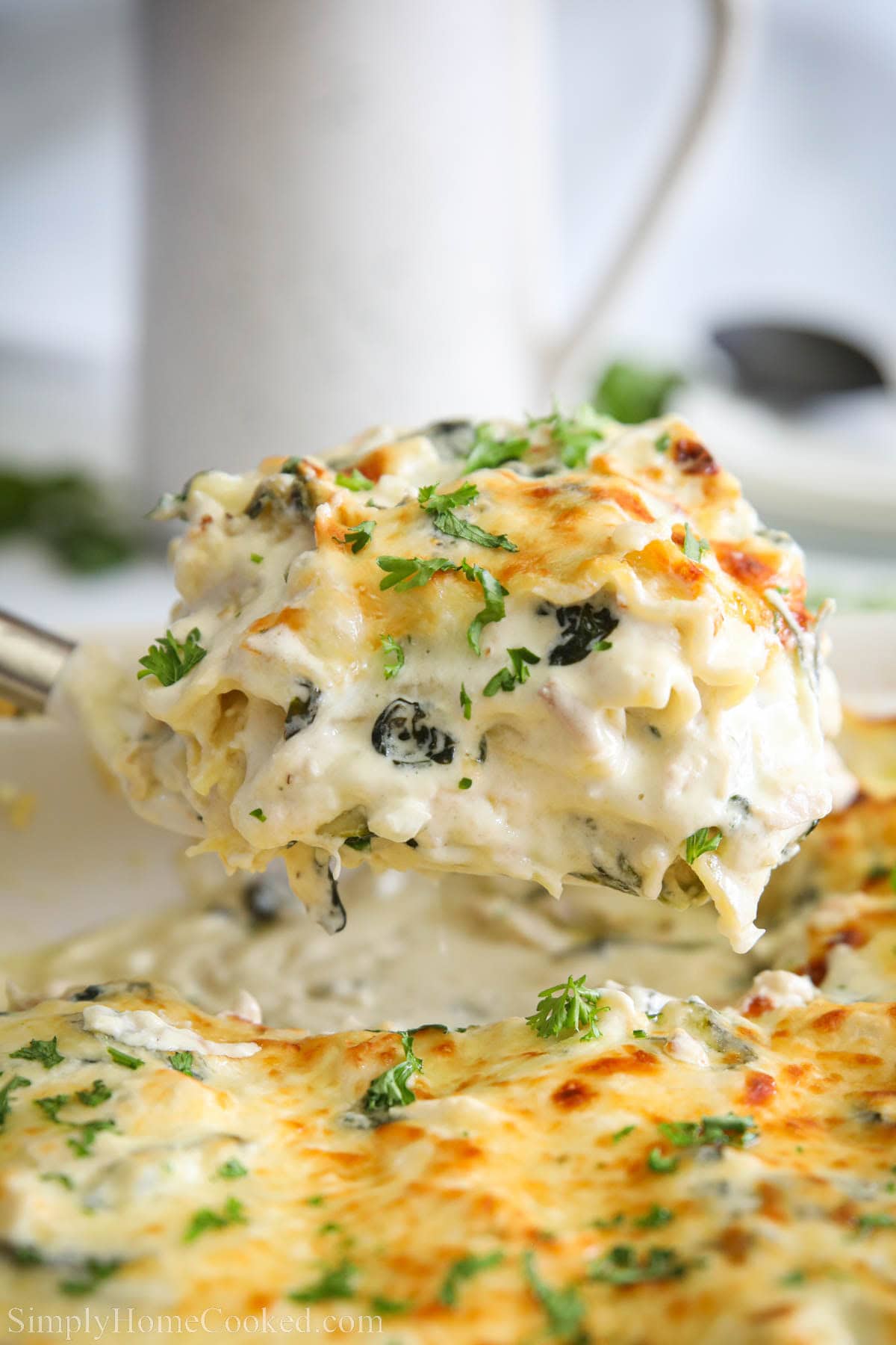 Slice of Chicken Alfredo Lasagna being lifted out of the pan. 