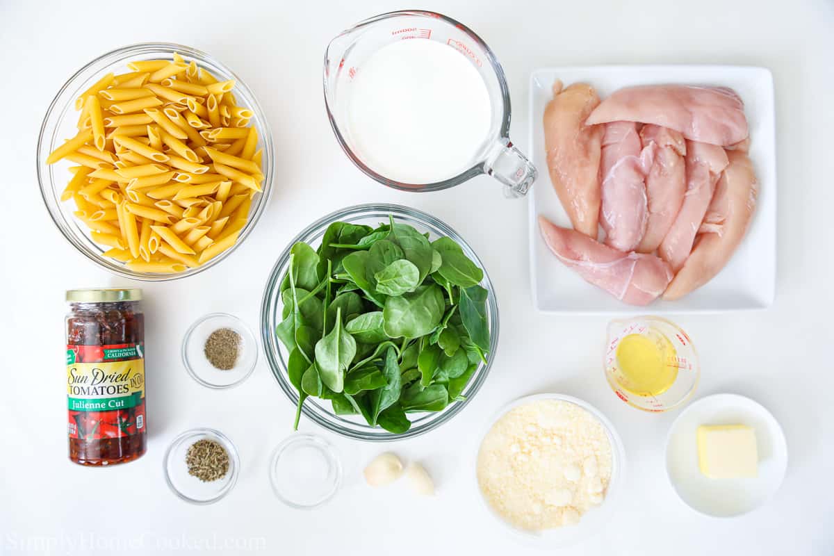 Ingredients to make Creamy Tuscan Chicken Pasta, including penne pasta, fresh spinach, heavy cream, chicken, sun dried tomatoes, oil, butter, parmesan cheese, garlic, salt, pepper, and Italian seasoning.