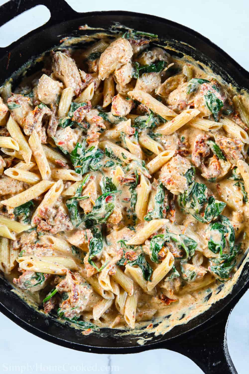 Creamy Tuscan Chicken Pasta in a cast iron skillet.
