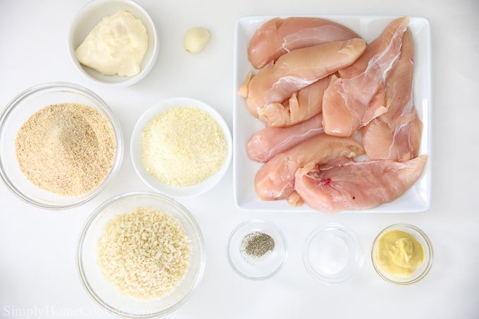 Ingredients for breaded air fryer chicken tenders, including raw chicken, flour, Panko, Parmesan cheese, garlic, mayonnaise, Dijon mustard, salt and pepper.