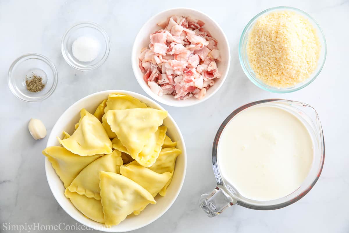 Ingredients for Chicken and Cheese Ravioli, including ravioli, bacon, heavy cream, Parmesan cheese, salt, pepper, and a garlic clove on a white background.