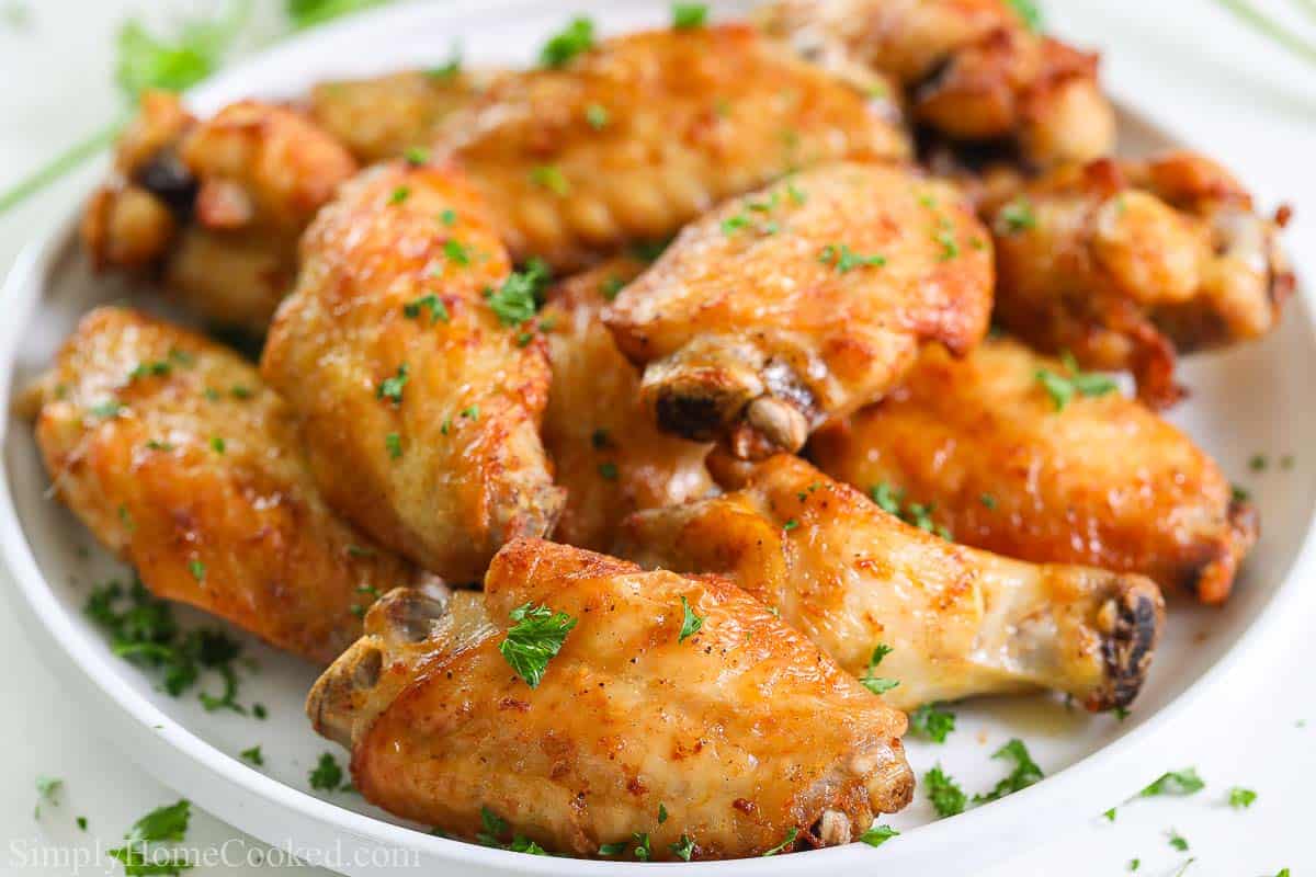 up close image of crispy air fryer chicken wings on a white plate with chopped parsley on top