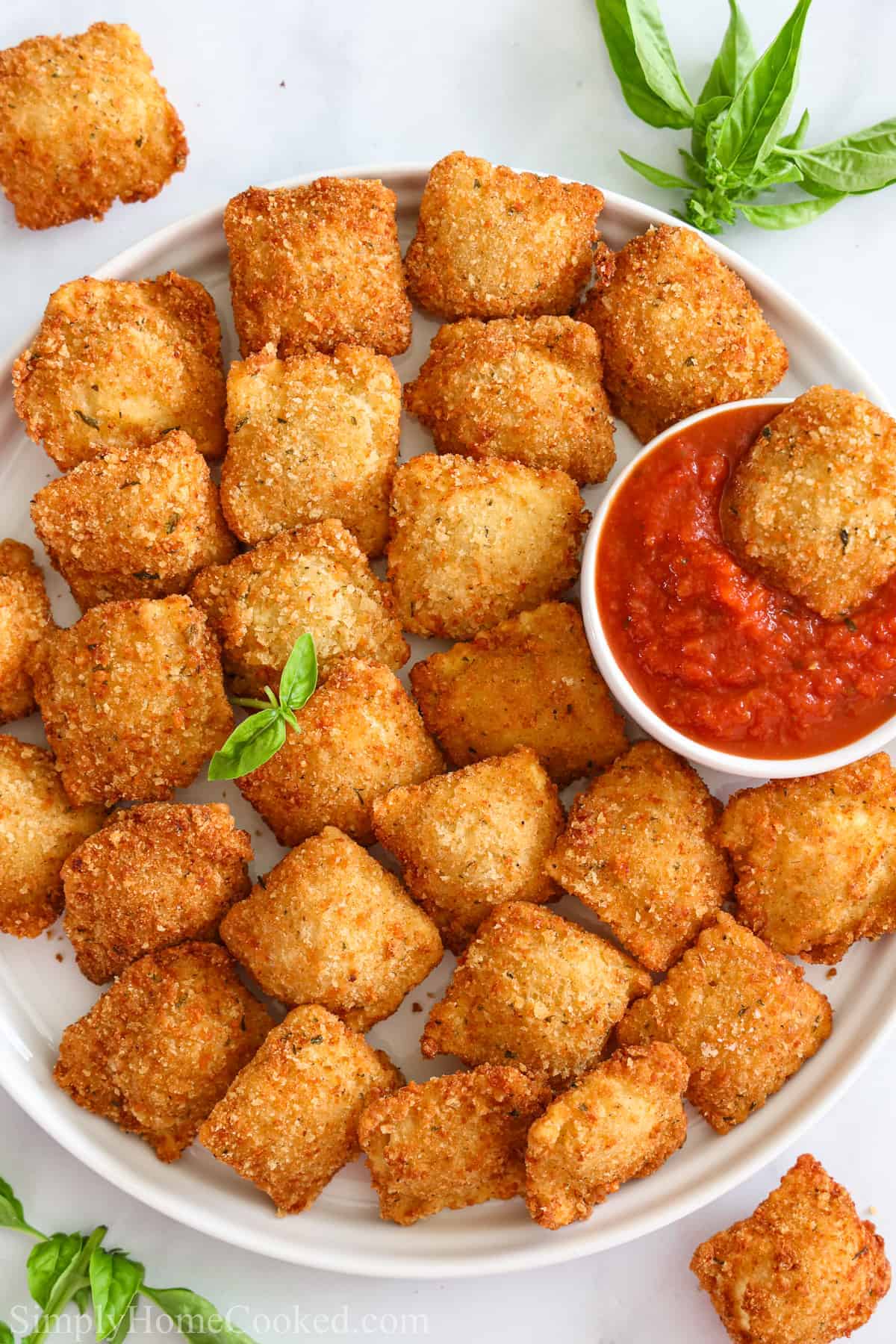 Plate of Crispy Fried Ravioli, with one in a marinara dipping sauce.