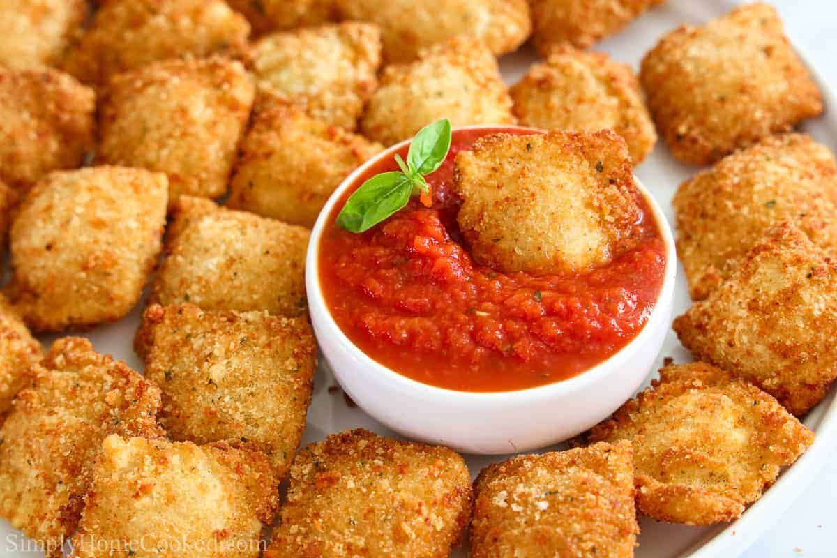 Close up of Crispy Fried Ravioli with a a bowl of marinara sauce and one ravioli inside.