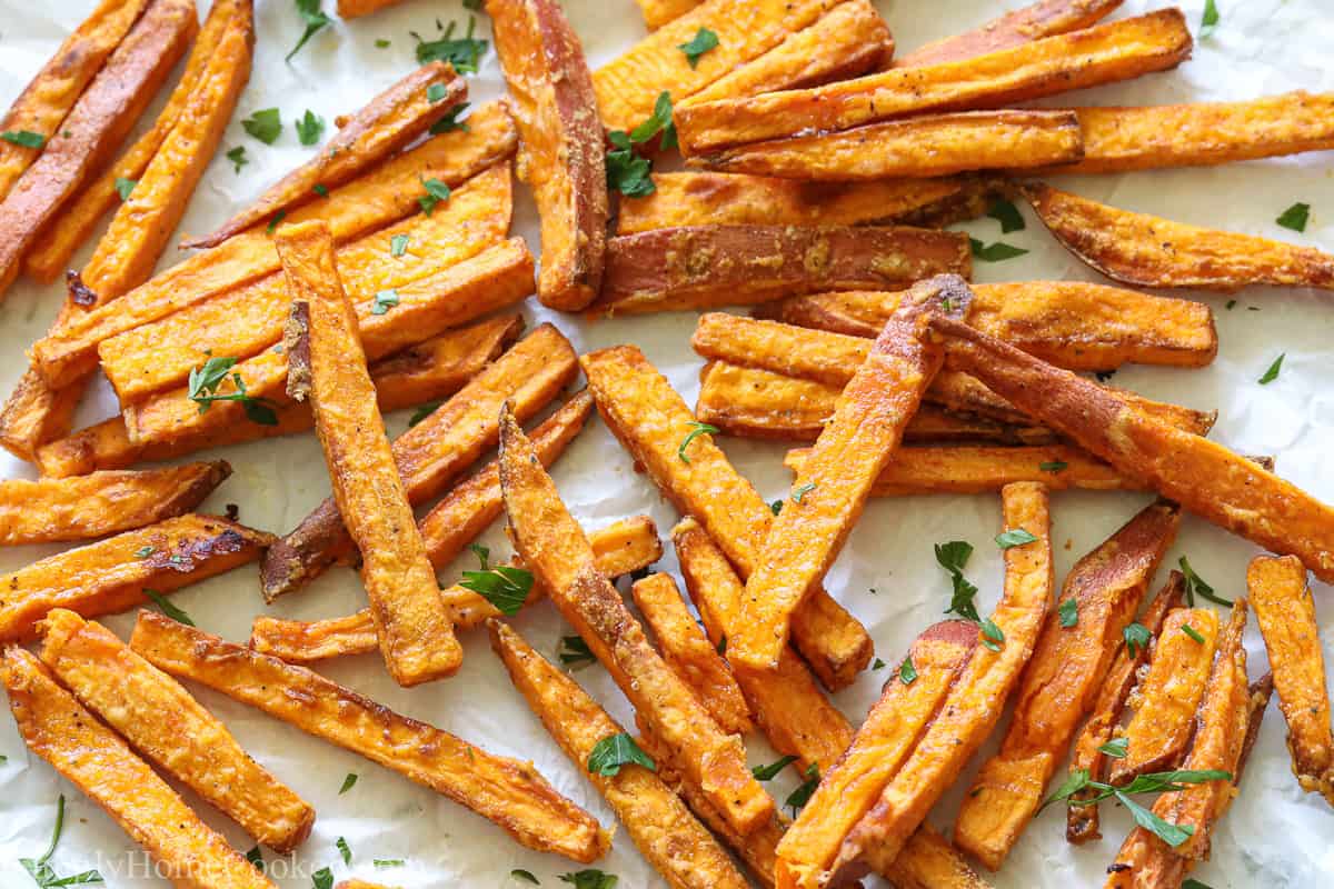 The BEST Air Fryer Sweet Potato Fries on a white background with parsley sprinkled on top.