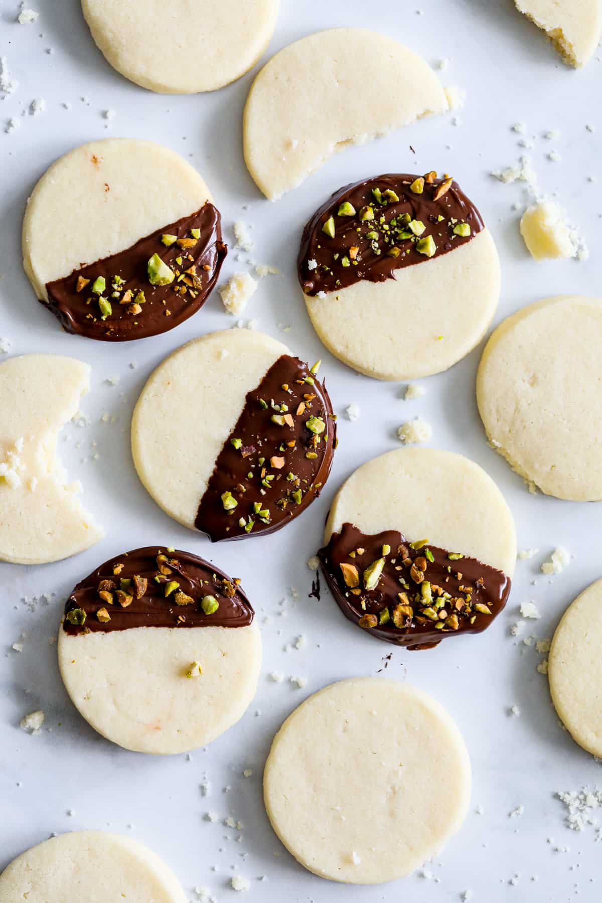Tray of Classic Shortbread Cookies, some dipped in chocolate and sprinkled with chopped pistachios, with some crumbs in the background.