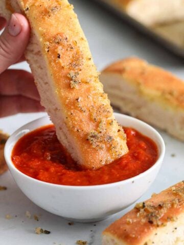 close up image of a copycat pizza hut breadstick being dipped into a bowl or marinara sauce