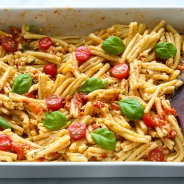 Baking dish with Baked Feta Pasta mixed with a wooden spoon