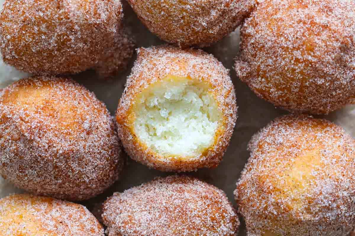 Cinnamon sugar donut holes, one with a bite missing. 