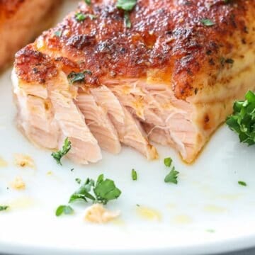 close up horizontal image of forked salmon on a white plate