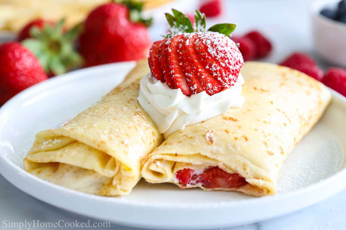 Folded crepes filled with whipped cream and strawberries, then topped with more