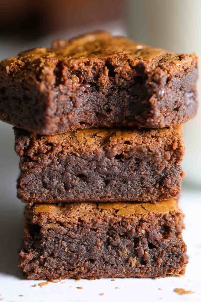 Easy 4 ingredient Nutella brownies from scratch, that are gluten-free! The best homemade brownie recipe that will make you never eat brownie box mix again. #brownies #nutellabrownies #fudgebrownies #brownierecipe #homemadebrownies #easybrownies Nutella Brownies stacked on top of each other, one with a bite missing