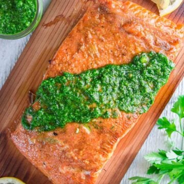 Vertical image of Cedar Plank Salmon with chimichurri sauce on top