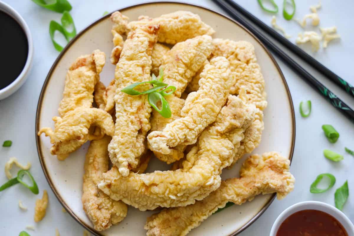 Horizontal image of Chicken Tempura with chopsticks and sauces nearby