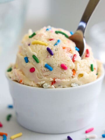 Vertical image of Edible Sugar Cookie Dough with rainbow sprinkles in a white cup
