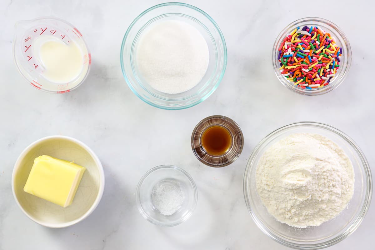Ingredients for Edible Sugar Cookie Dough, including  flour, milk, butter, sugar, vanilla, sat, and rainbow sprinkles.