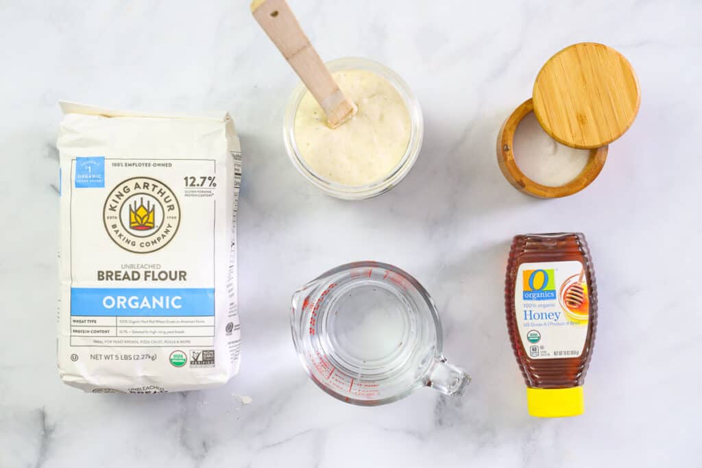 Ingredients for Sourdough Bagels, including sourdough starter, water, bread flour, honey, and salt.