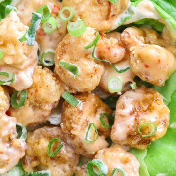square image of homemade bang bang shrimp on a bed of butter lettuce