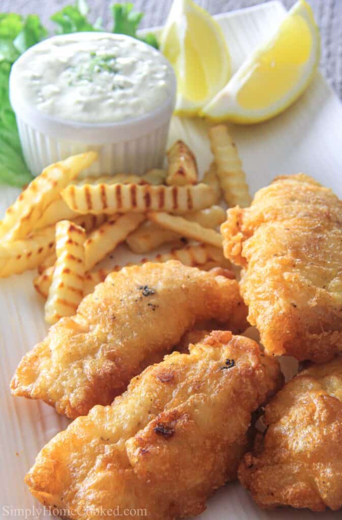 Vertical image of Beer Batter Cod with French fries, lemon slices, and tartar sauce