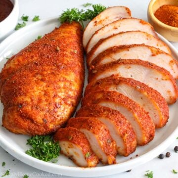 Square image of Smoked Chicken Breast sliced on a plate with a parsley garnish