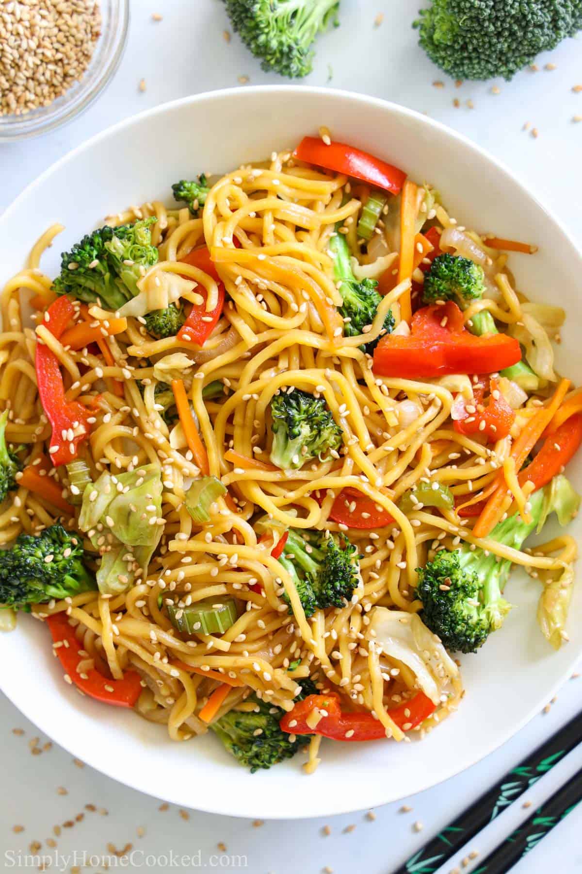 This delicious vegetable chow mein is loaded with stir-fried vegetables, thick yakisoba noddles, and an easy Asian sauce that takes this dish to the next level. #chowmein #yakisoba #asiannoodles #ramen #vegetablechowmein #stirfriednoodles Vertical image of a plate of Chow Mein with sesame seeds sprinkled on top
