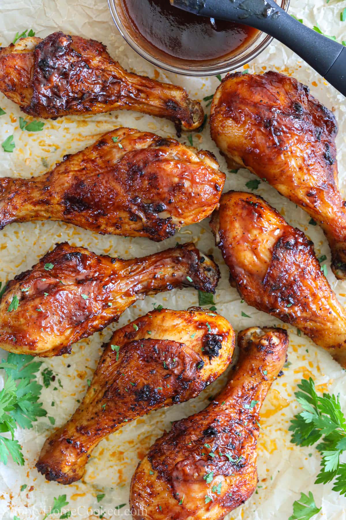 These BBQ Air Fryer Chicken Legs have crispy skin smothered in BBQ sauce & tender meat that's been rubbed with flavorful spices. It's delish! #BBQchicken #BBQchickenlegs #airfryerBBQchickenlegs #BBQairfryerchickenlegs Vertical image of Air Fryer Chicken Legs with BBQ sauce