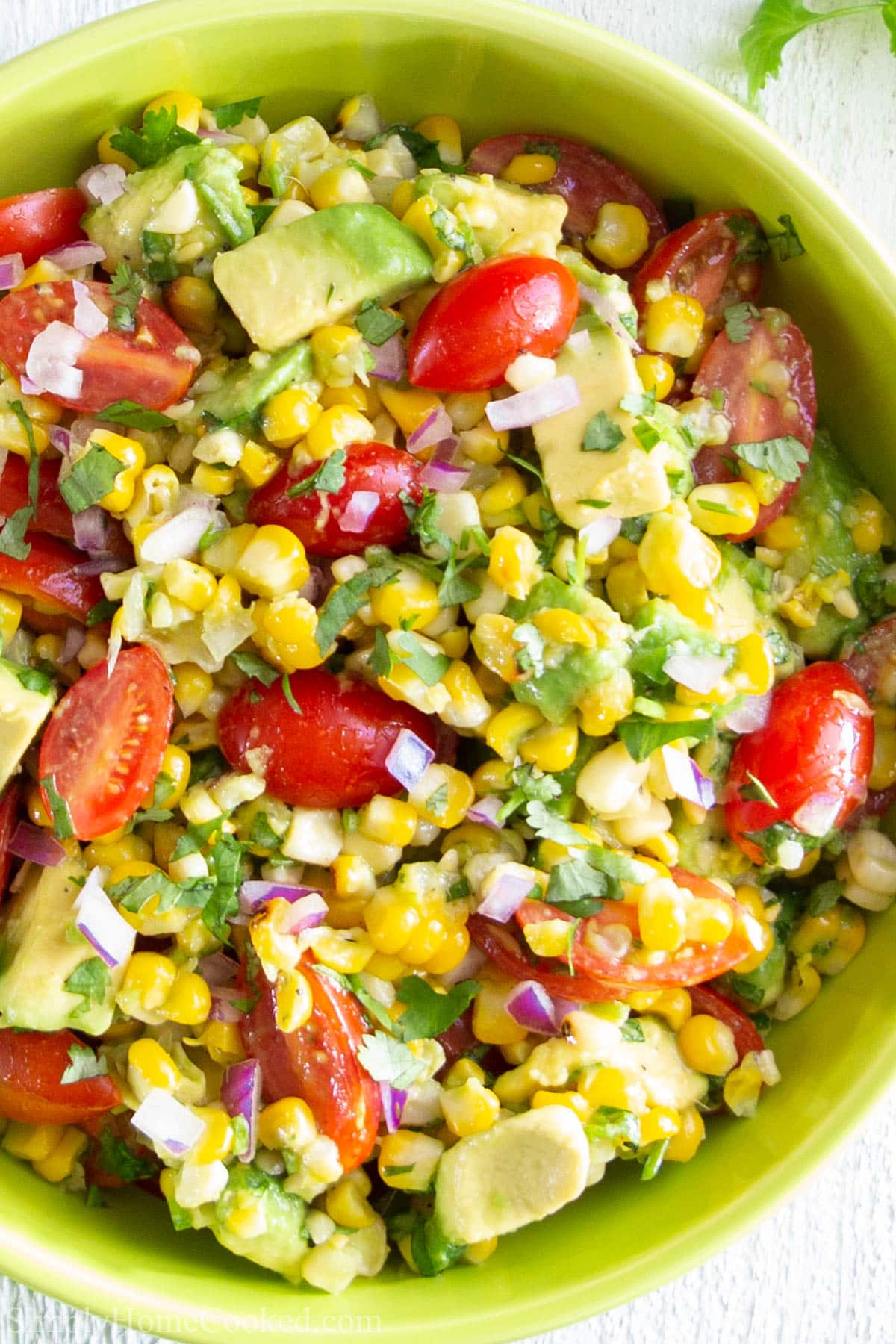 This Avocado Corn Salad is loaded with flavors from the sweet grilled corn, avocado, cherry tomatoes, and homemade lime dressing. This sweet summer corn salad is easy to make and super irresistible. #cornsalad #avocadocornsalad #summersalad #avocadosalad Vertical closeup image of Avocado Corn Salad