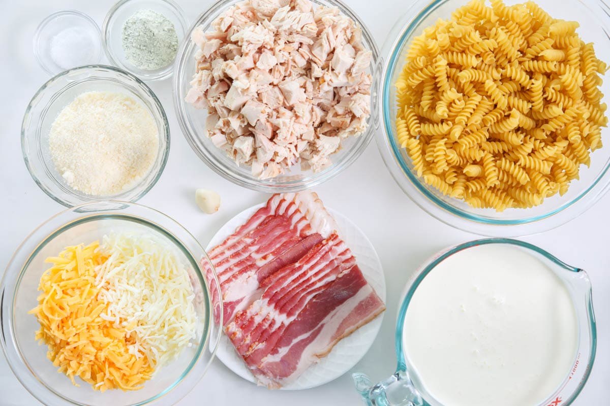 Ingredients for Chicken Bacon Ranch Pasta, including pasta, bacon, ranch seasoning, cream, garlic, chicken, salt, and cheese.